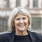 Portraitfoto Rita Baus, Frau mit blonden Haaren und schwarzem Tshirt und schwarzer Jacke