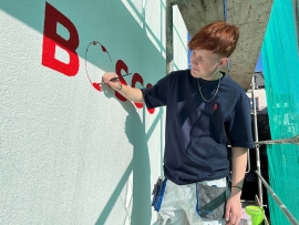 Maler beim Anbringen des Logos an Fassade