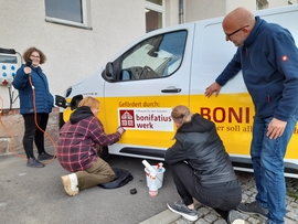 Auszubildende Mediengestalter bei der Folierung des Boni-Busses